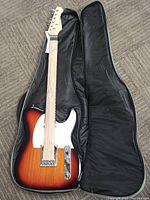 Electric guitar with sunburst finish inside black padded carrying case showing front body and neck.