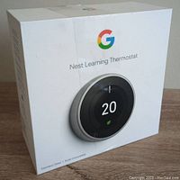 Sealed retail box of Google Nest Learning Thermostat with image and brand logo on front showing stainless steel model.
