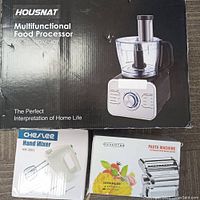 Photo showing boxes of Housnat multifunctional food processor, Cheslee hand mixer, and Nuvantee pasta machine.