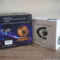 Boxes of two different magnetic levitating globes showing product details and branding