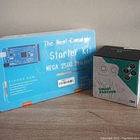 Photo showing ELEGOO Mega 2560 Project Starter Kit blue plastic case next to Remoking Smart Partner robot box