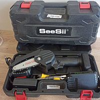 One SeeSii mini chainsaw open in its case showing the black and orange electric chainsaw with 4-inch chain blade, battery, charger, and small tools