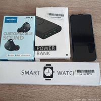 Overview of four items: earbuds, power bank, smartphone, smartwatch