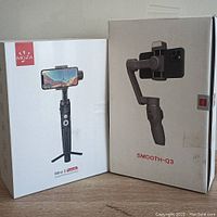 Boxes of MOZA Mini-S Essential and Zhiyun-Tech Smooth-Q3 smartphone gimbals side by side.
