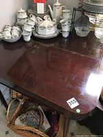 Top view of dark wood table with visible surface wear, some scratches and marks. Table shows seller's lot number sticker '355' and a green dot.