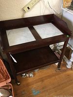Full view of dark wood cart with marble top and wheels on legs