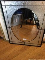 Front view of rectangular etched glass wall mirror with oval central mirror and etched wheat grass sides.