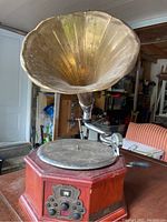 Full view of the antique record player showing the large brass horn speaker and wooden base with turntable.