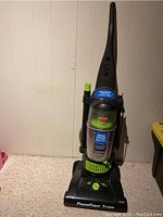 Front view of Bissell Model 68C7D upright vacuum with PowerForce Turbo label, hose attached to side and green dial on base.