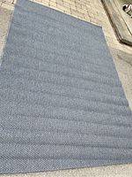 Full view of the large grey rectangular rug laid out flat on a hard surface, showing its size and shape.