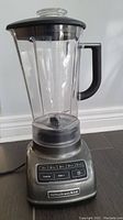 Full view of KitchenAid blender showing pitcher, black handle, lid, and metallic gray base with control panel.