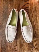 Top view of cream-colored Lacoste ladies loafer showing burgundy stitching and leather upper.