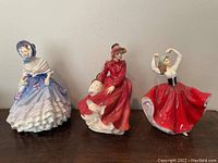 Front view of three figurines: blue-dress, red-dress, red-skirt dancing