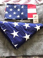 Close-up of one American flag folded triangularly, showing blue field with white stars and attached label