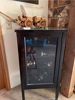 Full view of black wood and glass cabinet with glass figurines inside.