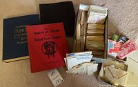 Photo showing three albums and a large collection of loose stamps in envelopes and small packets.