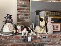 Overview of various stuffed animals and wooden bird figurines arranged on a brick surface with a framed picture visible behind them