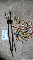 Photo of varied collector pins showing numerous designs and shapes, spread on carpet.
