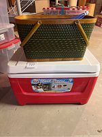 Woven picnic basket stacked on top of red Igloo cooler with Island Breeze label.