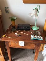 Wooden end table holding all items: two lamps, clock radio, ceramic duck figurine