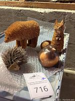 Four animal figurines made from fibers and wood, including bear, bird, hedgehog, and squirrel on plastic tray with bubble wrap.