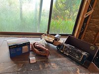 Wide view of lot showing vintage toy truck, baseball mitt, boxed model car, and boxed telephone on wooden surface.