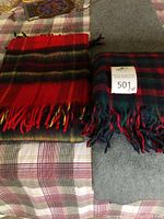 Two throw blankets laid next to each other showing their plaid patterns and fringed ends.