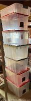 Stack of seven clear plastic storage bins outdoors or in basement area with wooden beam visible