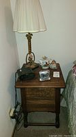 Full view of side table with lamp, clocks, teapot and doll on top