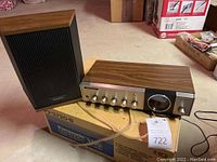 Panasonic stereo receiver with wooden exterior and matching speaker on a box in basement setting