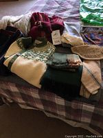 Image showing wool sweaters, scarves, and gloves arranged on a plaid bedspread.