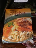 Cover of 'Simply Chicken' cookbook showing plated cooked chicken breast, rice, and orange slices.