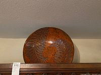 Round decorative bowl with carved leaf details, medium brown color