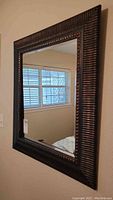 Full view of rectangular beveled mirror showing overall black and goldfish colored frame.