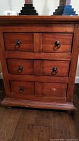 Full front view of one wood night stand showing three drawers with ring pull handles, one drawer missing ring