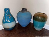 Three vases on floor showing full lot: one pottery and two Lenox crystal vases in turquoise and brown tones.