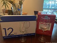 Photo of the boxed 12 pieces all-purpose wine glasses and a box of Martha Stewart Holiday Garden glassware set with two glasses outside showing size and style