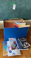 Photo of a blue box with various books inside and displayed in front.