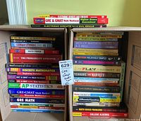 Photo showing a large collection of various educational books mostly on GRE, GMAT, AP Statistics, mathematics, electronics, and other science-related topics stacked in two boxes.