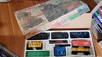 Top-down photo showing train set components neatly arranged inside original cardboard box with vintage train graphics.