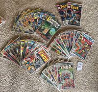 Four fanned stacks of bagged Captain America and Thor comics laid on carpet