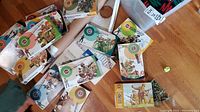 Overview of scattered Airfix model soldier boxes, rolled paper plans partially visible, and paper airplane kit