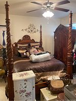 View of the four poster bed shown fully assembled with linens and cushions, highlighting the thick twisted posts and rich wood tone.
