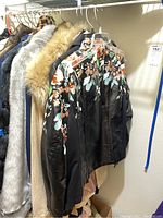 Photo showing a row of jackets and coats including black leather embroidered jackets and various faux fur coats in grey, beige, brown, and leopard print.