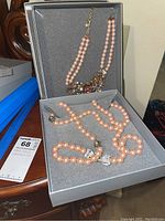 Two necklaces displayed in open jewelry boxes. One is pink faux pearl-style beads and the other features multi-colored floral beads and gold-tone chains.