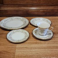 Image showing a collection of Lenox Castle Garden china pieces including various plates and a teacup, all featuring gold and floral detailing.