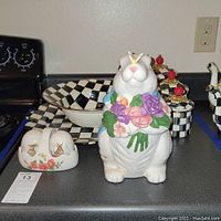 Front view of scalloped metal tray, checkered bowl, canisters, salt and pepper shakers, and bunny jar.