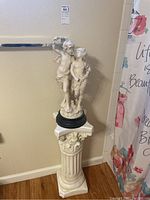 Full view of resin pedestal with statue on top, showing damage on pedestal bottom