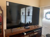 Front view of TV on stand with remotes on surface