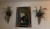 Full view of the painting centered on the wall flanked by two decorative metal wall sconces with faux flower arrangements, showing the overall lot setup